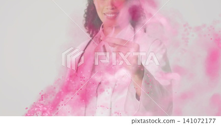 Pointing doctor wearing white lab coat and stethoscope gesturing in studio, with pink powder Pointing doctor wearing white lab coat and stethoscope gesturing in studio, with pink powder 141072177