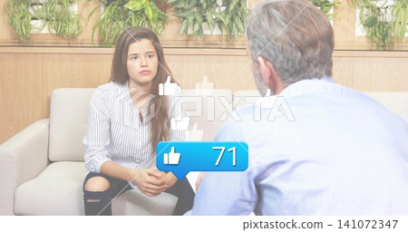 Talking teen wearing striped top and ripped jeans on sofa in lounge, with thumbs-up 71 bubble 141072347