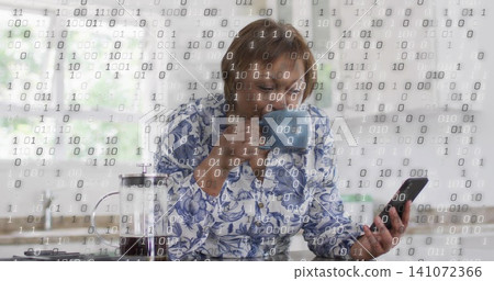 Sipping woman wearing blue blouse, checking smartphone, lifting blue mug in kitchen, binary overlay Sipping woman wearing blue blouse, checking smartphone, lifting blue mug in kitchen, binary overlay 141072366