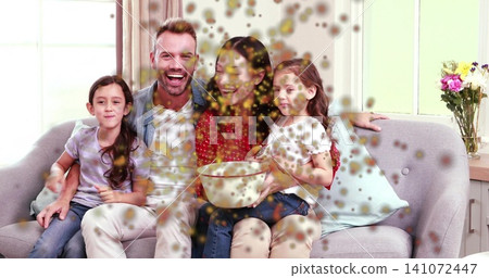 Sitting family of four on light-grey sofa at home, mother wearing red blouse holding bowl, blotches Sitting family of four on light-grey sofa at home, mother wearing red blouse holding bowl, blotches 141072447