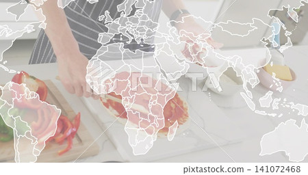 Spreading teen wearing striped apron and watch making pizza on marble counter, board, map overlay Spreading teen wearing striped apron and watch making pizza on marble counter, board, map overlay 141072468