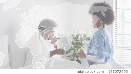 Offering caregiver in scrubs handing pill while senior sipping water at bedside, map overlay Offering caregiver in scrubs handing pill while senior sipping water at bedside, map overlay 141072493