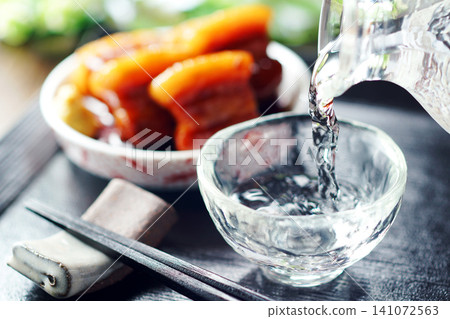 Sake is poured and braised pork belly is served. Sake is poured and braised pork belly is served. 141072563