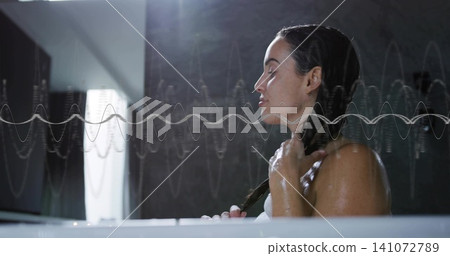 Holding wet braid, adult woman in towel sitting in bathtub near window with waveform, copy space Holding wet braid, adult woman in towel sitting in bathtub near window with waveform, copy space 141072789