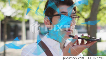 Speaking into phone, Asian man on shaded sidewalk wearing shirt, glasses, brown strap, blue overlay Speaking into phone, Asian man on shaded sidewalk wearing shirt, glasses, brown strap, blue overlay 141072790
