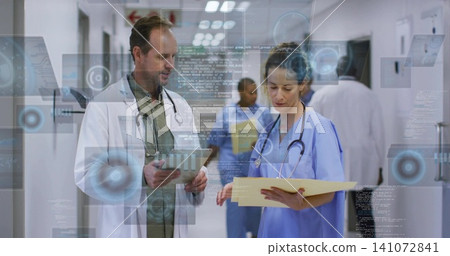 Consulting staff in white coats and blue scrubs in hospital hall, holding tablet and yellow folder Consulting staff in white coats and blue scrubs in hospital hall, holding tablet and yellow folder 141072841