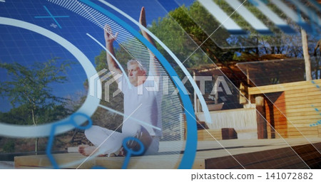 Stretching senior man raising arms cross-legged on wood deck by cabin wearing white-wear AR overlay Stretching senior man raising arms cross-legged on wood deck by cabin wearing white-wear AR overlay 141072882