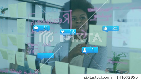 Pointing woman in gray blazer touching glass wall at office, yellow sticky notes and social icons Pointing woman in gray blazer touching glass wall at office, yellow sticky notes and social icons 141072959