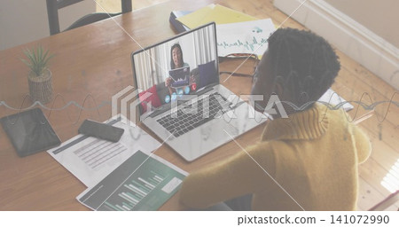 Sitting woman wearing mustard sweater watching remote presenter on laptop at home office, charts Sitting woman wearing mustard sweater watching remote presenter on laptop at home office, charts 141072990