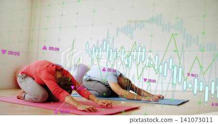 Practicing pair holding child's pose in yoga studio, coral top, blue tee, mats, data overlays Practicing pair holding child's pose in yoga studio, coral top, blue tee, mats, data overlays 141073011