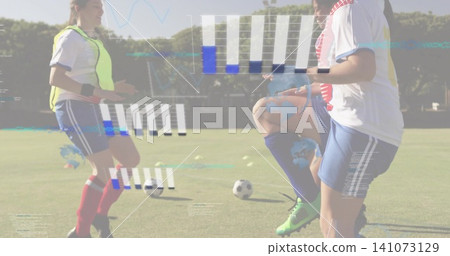Practicing female players in kit running drill on grass pitch with balls, neon bib and data 141073129