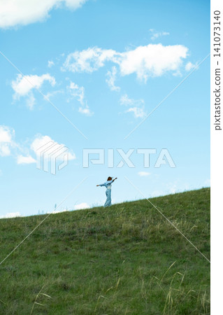 Woman Walking in a Green Field on Rolling Hills, Embracing Freedom and Nature Woman Walking in a Green Field on Rolling Hills, Embracing Freedom and Nature 141073140