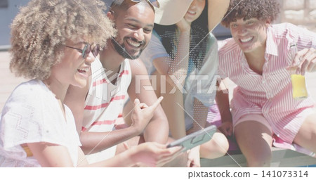 Laughing friends leaning around tablet on sunny deck, wearing sunhat, shades, holding yellow bottle Laughing friends leaning around tablet on sunny deck, wearing sunhat, shades, holding yellow bottle 141073314