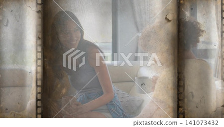 Smiling woman, man sitting on sofa near window, holding mug, plaid shirt tied, film-strip overlay Smiling woman, man sitting on sofa near window, holding mug, plaid shirt tied, film-strip overlay 141073432