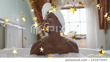 Laughing woman soaking in bubble bath in attic bathroom, wearing towel turban with gold confetti Laughing woman soaking in bubble bath in attic bathroom, wearing towel turban with gold confetti 141073447