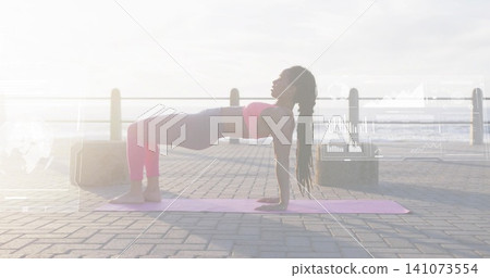 Holding reverse plank, woman exercising on seaside promenade with pink mat, crop top, leggings Holding reverse plank, woman exercising on seaside promenade with pink mat, crop top, leggings 141073554
