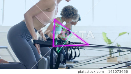 Pulling front woman pulling reformer straps in bright pilates studio, wearing pink sports bra Pulling front woman pulling reformer straps in bright pilates studio, wearing pink sports bra 141073666