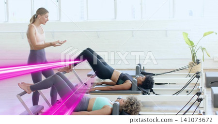 Bridging centered participant wearing black workout set on Pilates reformer at studio, with straps Bridging centered participant wearing black workout set on Pilates reformer at studio, with straps 141073672