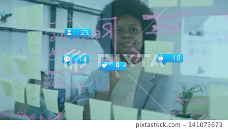 Pointing woman in turtleneck blazer marking glass at office with yellow sticky notes and blue likes Pointing woman in turtleneck blazer marking glass at office with yellow sticky notes and blue likes 141073673