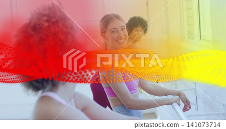 Smiling woman leaning on ballet barre in studio, in lilac bra, gray leggings, red-yellow overlay Smiling woman leaning on ballet barre in studio, in lilac bra, gray leggings, red-yellow overlay 141073714