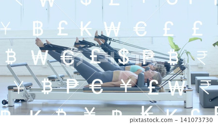 Doing Pilates, three women lying on reformers in Pilates studio wearing leggings currency overlay Doing Pilates, three women lying on reformers in Pilates studio wearing leggings currency overlay 141073730