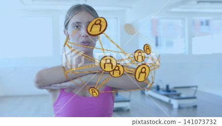 Standing woman crossing arms in pink tank top in fitness studio, digital overlay, Pilates reformers Standing woman crossing arms in pink tank top in fitness studio, digital overlay, Pilates reformers 141073732