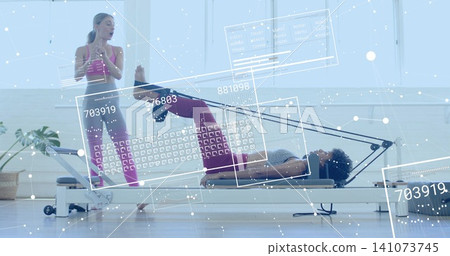 Performing client lifting hips on reformer at studio with holographic UI, wearing maroon leggings 141073745