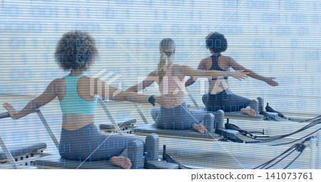 Doing three women wearing sportswear practicing pilates on reformers in studio with straps Doing three women wearing sportswear practicing pilates on reformers in studio with straps 141073761