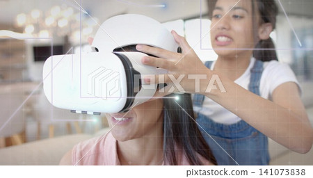 Placing white VR headset, teenager in overalls adjusting adult wearing top in lounge, HUD overlay Placing white VR headset, teenager in overalls adjusting adult wearing top in lounge, HUD overlay 141073838