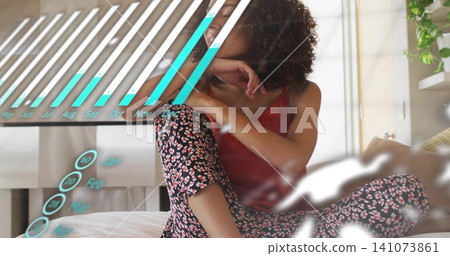 Sitting woman wearing red cami, floral pajamas on bed in bedroom, showing turquoise hologram chart Sitting woman wearing red cami, floral pajamas on bed in bedroom, showing turquoise hologram chart 141073861
