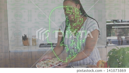 Smiling woman holding salad plate at kitchen island wearing striped dress, green circuit overlay Smiling woman holding salad plate at kitchen island wearing striped dress, green circuit overlay 141073869