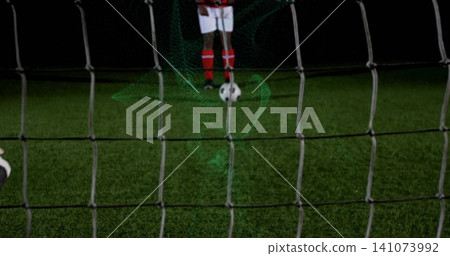 Positioning player lining up shot on soccer pitch at night, net, ball, white shorts, red socks Positioning player lining up shot on soccer pitch at night, net, ball, white shorts, red socks 141073992