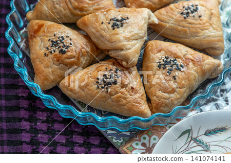 Traditional Asian samsa with sesame seeds on a decorative plate. Uzbek food Traditional Asian samsa with sesame seeds on a decorative plate. Uzbek food 141074141