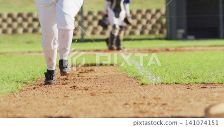 Running baseball player sliding toward plate on school field, showing white pants and black cleats Running baseball player sliding toward plate on school field, showing white pants and black cleats 141074151