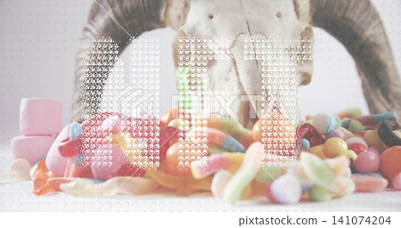 Displaying bleached horned skull sitting on white tabletop, showing gummy worms and jellybeans 141074204