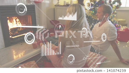 Sitting couple holding red mugs, in pajamas and T-shirt by fireplace at home, with HUD overlays Sitting couple holding red mugs, in pajamas and T-shirt by fireplace at home, with HUD overlays 141074239