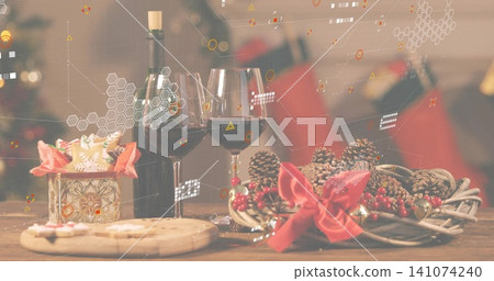 Showing holiday scene on wooden table at home, with two wine glasses, green bottle, wreath, cookies 141074240