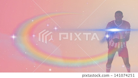 Standing man in striped jersey, shorts in studio with rainbow arc, sparkles, lens flare, copy space 141074251