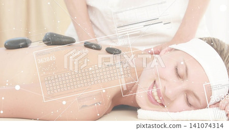 Placing therapist hands adjusting black stones along prone client spine at spa, white uniform, HUD Placing therapist hands adjusting black stones along prone client spine at spa, white uniform, HUD 141074314