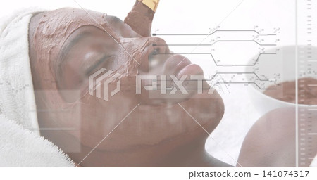 Receiving spa client on treatment bed, applying brown mask with brush, wearing white towel, overlay Receiving spa client on treatment bed, applying brown mask with brush, wearing white towel, overlay 141074317