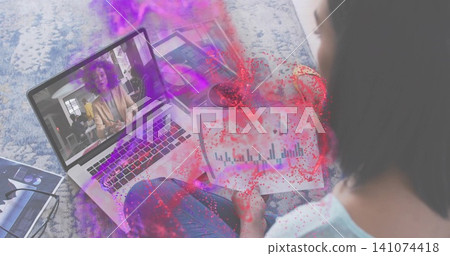 Studying woman in light blue top holding charts watching laptop on patterned rug, home, copy space Studying woman in light blue top holding charts watching laptop on patterned rug, home, copy space 141074418