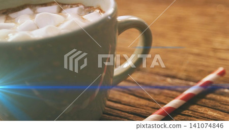 Sitting ceramic mug steaming on wooden table, mini marshmallows, red straw, blue lens flare Sitting ceramic mug steaming on wooden table, mini marshmallows, red straw, blue lens flare 141074846