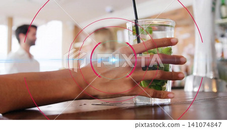 Holding adult hand gripping tall glass with mint-lime and straw on wood counter, with red overlay Holding adult hand gripping tall glass with mint-lime and straw on wood counter, with red overlay 141074847