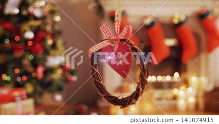 Hanging small twig wreath with red heart ornament and gingham ribbon in cozy living room Hanging small twig wreath with red heart ornament and gingham ribbon in cozy living room 141074915