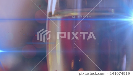 Showing tall narrow champagne flute sparkling in dim bar, with rising bubbles and blue lens flares Showing tall narrow champagne flute sparkling in dim bar, with rising bubbles and blue lens flares 141074919