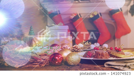 Displaying festive table scene glowing on wood surface in living room with desserts and red baubles Displaying festive table scene glowing on wood surface in living room with desserts and red baubles 141074923