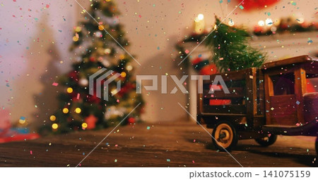 Showing wooden toy truck carrying fir branch on tabletop, Xmas tree, garland, confetti, copy space Showing wooden toy truck carrying fir branch on tabletop, Xmas tree, garland, confetti, copy space 141075159