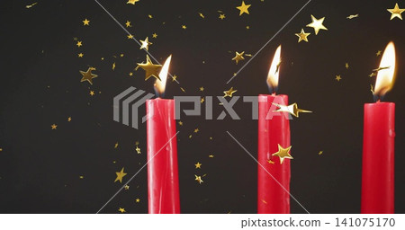 Glowing three red taper candles showing three visible flames in studio, with gold star confetti Glowing three red taper candles showing three visible flames in studio, with gold star confetti 141075170