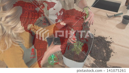 Repotting two women in apron at kitchen counter placing herb into planter with red malware overlay Repotting two women in apron at kitchen counter placing herb into planter with red malware overlay 141075261