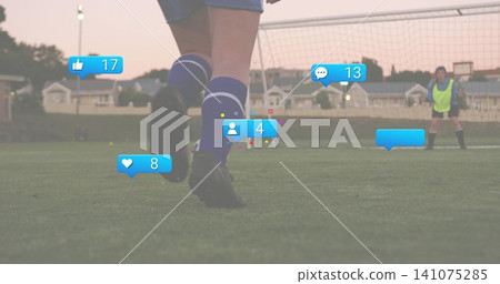 Soccer player wearing blue-knee-socks moving toward goal on turf at dusk, keeper in neon, overlays Soccer player wearing blue-knee-socks moving toward goal on turf at dusk, keeper in neon, overlays 141075285